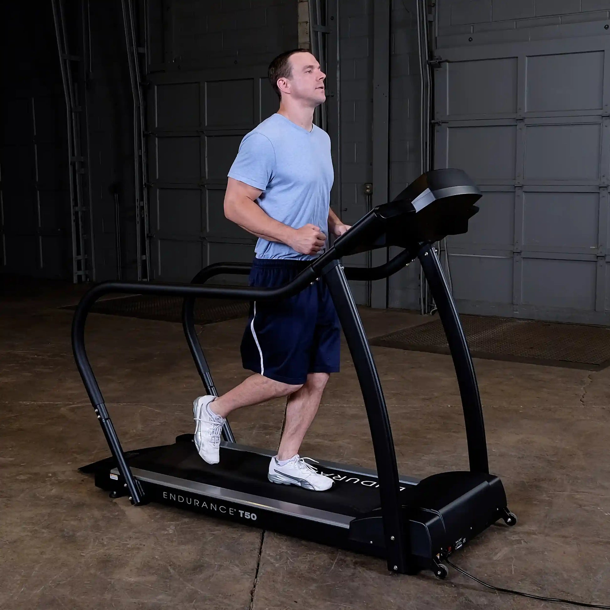 Man jogging on Endurance T50 treadmill in a garage setting.