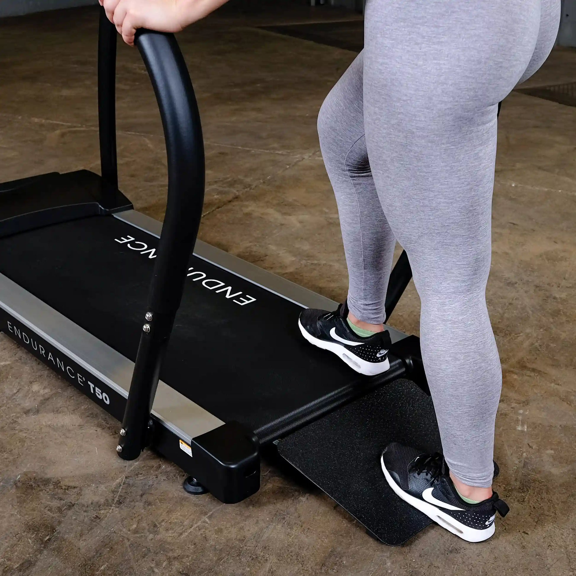 Person using Endurance T50 treadmill in gray leggings, focusing on leg workout.