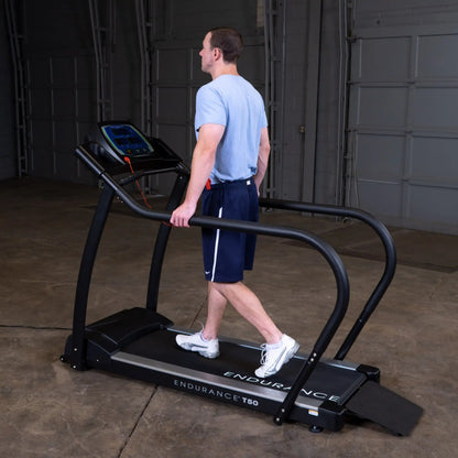 Man walking on Endurance T50 treadmill with safety rails in a garage gym.