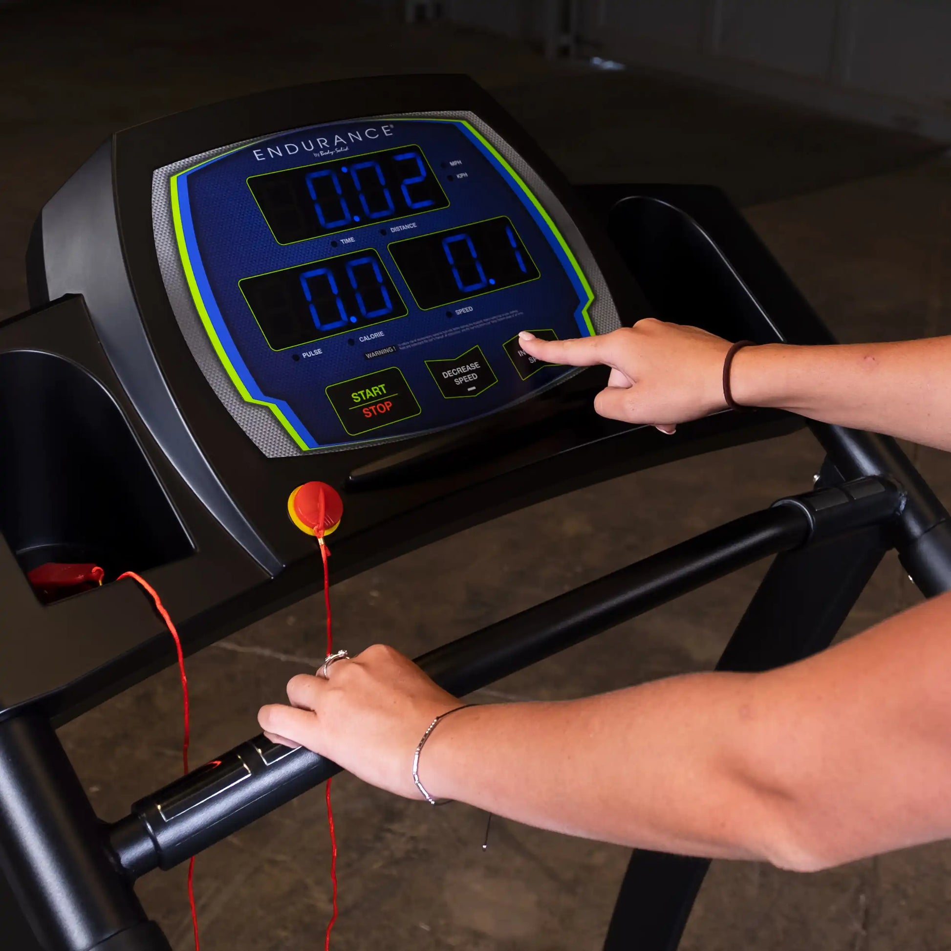 Endurance treadmill console with speed controls, user adjusting settings, featuring blue digital display.