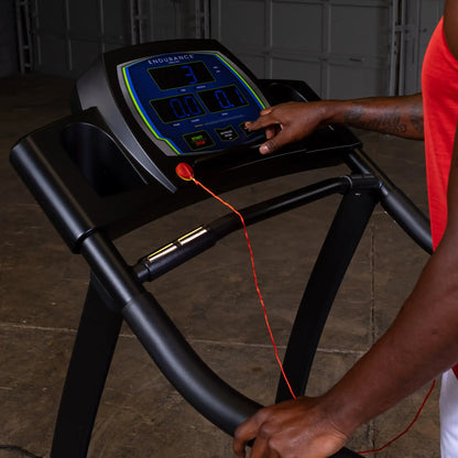 Endurance treadmill console with digital display in use by person in red tank top.