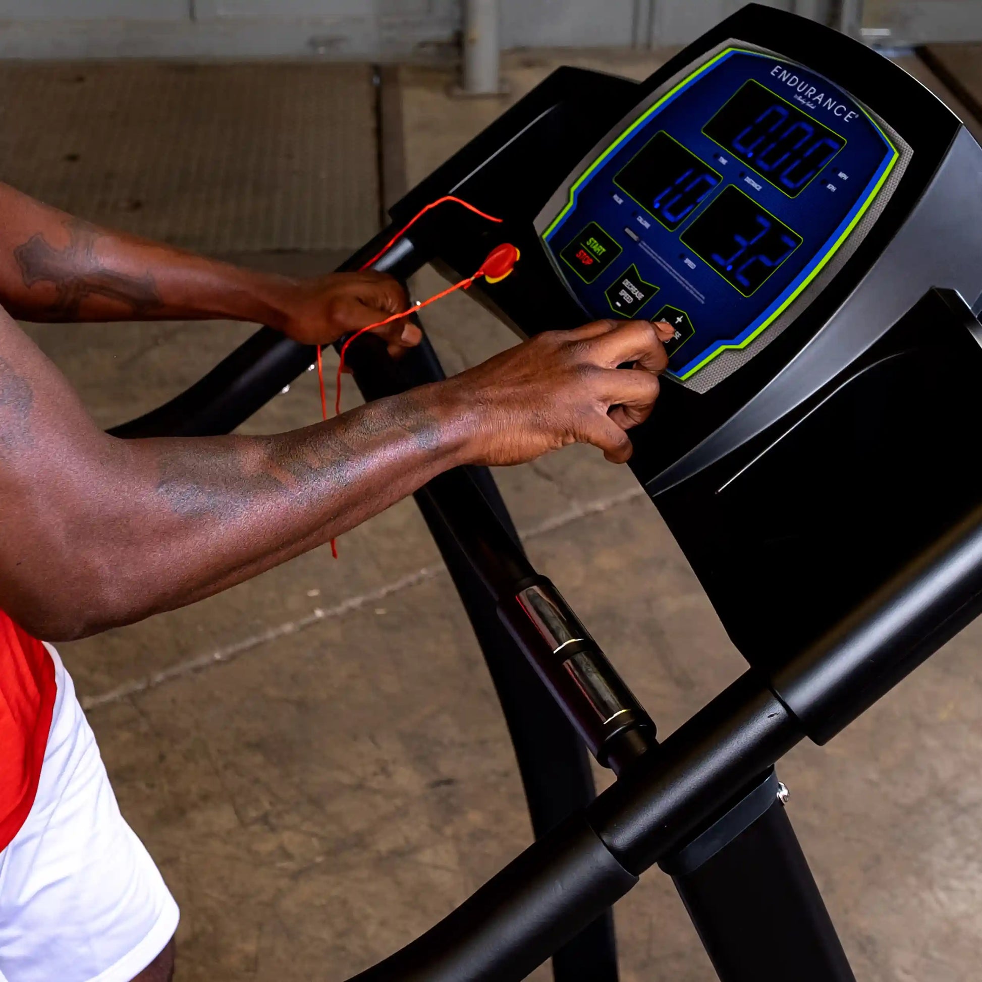 Man adjusting speed on Endurance treadmill display in gym.