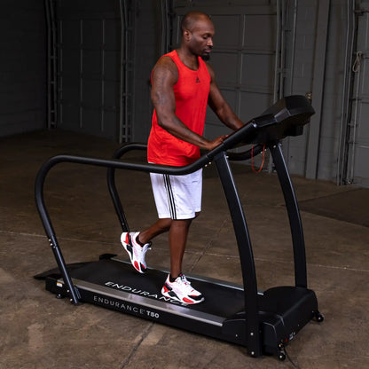 Man exercising on Endurance T50 treadmill in a red tank top in a garage setting.