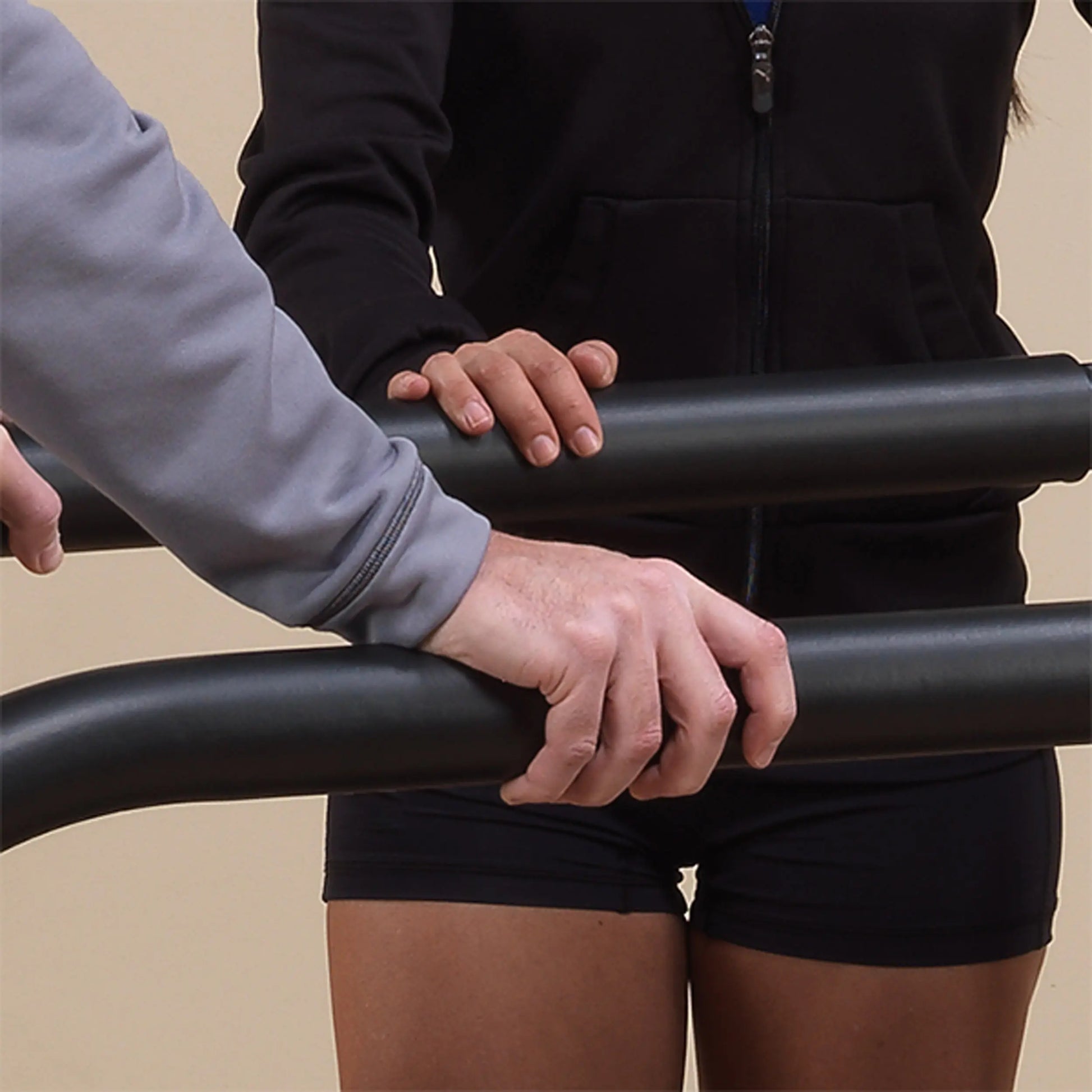 Physical therapist assisting patient with black parallel bars for rehabilitation.