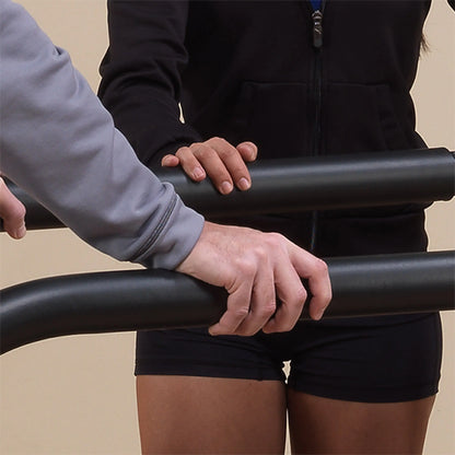 Physical therapist assisting patient with black parallel bars for rehabilitation.