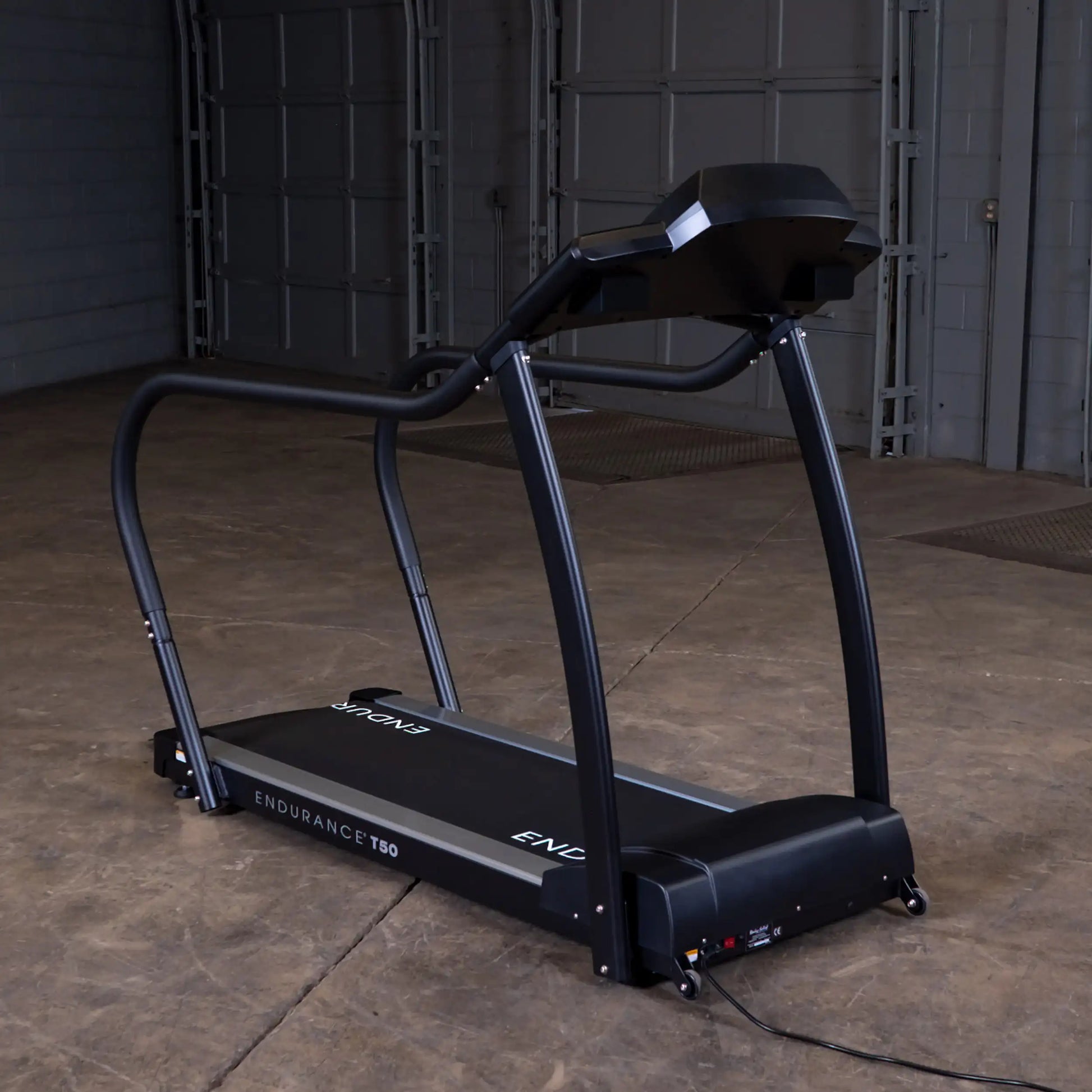 Endurance T50 treadmill with curved design in a spacious industrial setting.