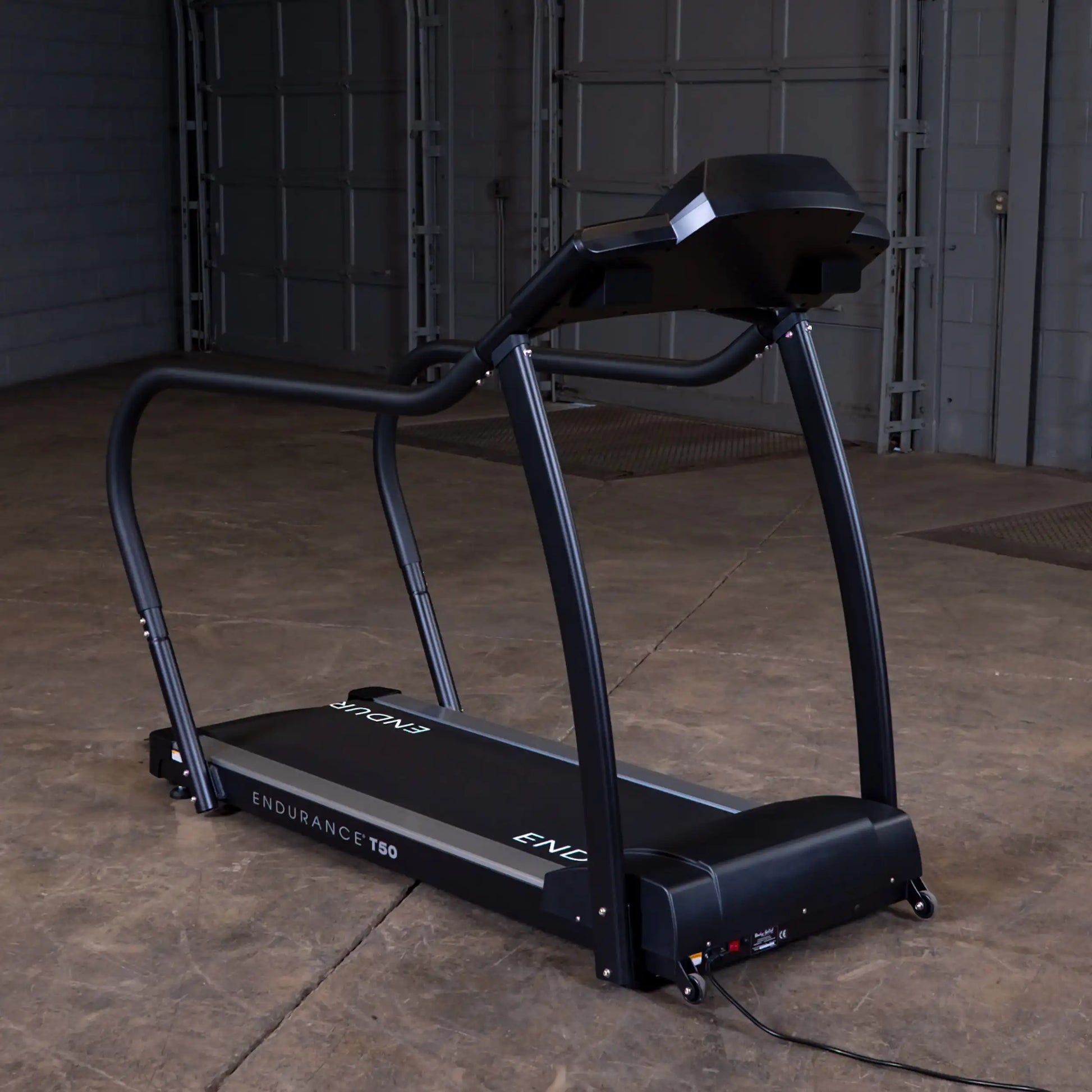 Endurance T50 treadmill with sleek black design in a spacious industrial setting.