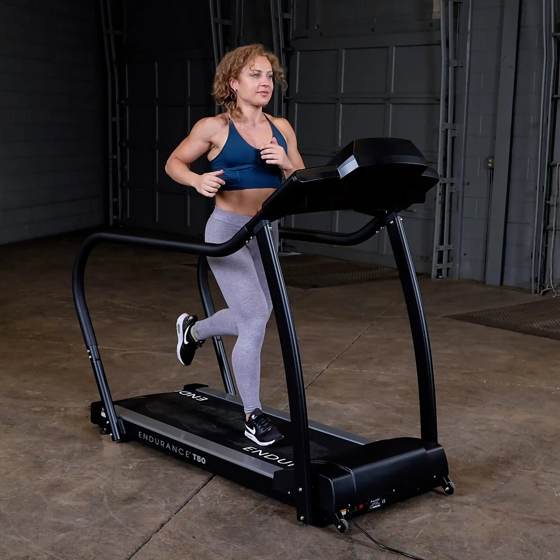Woman jogging on Endurance T50 treadmill in a warehouse gym.