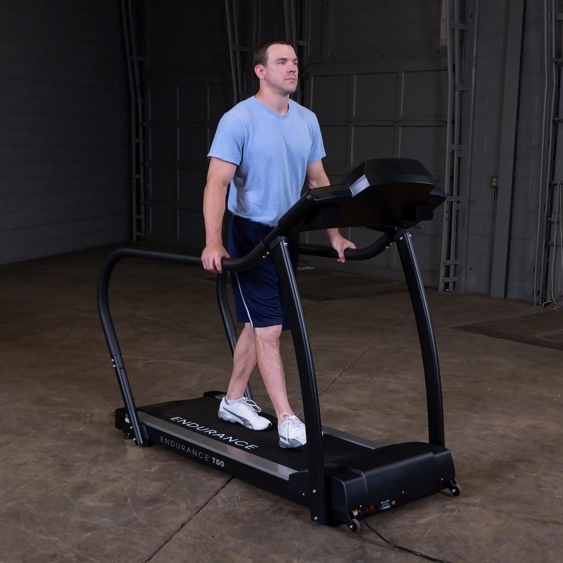 Man walking on Endurance T50 treadmill in blue shirt and shorts.