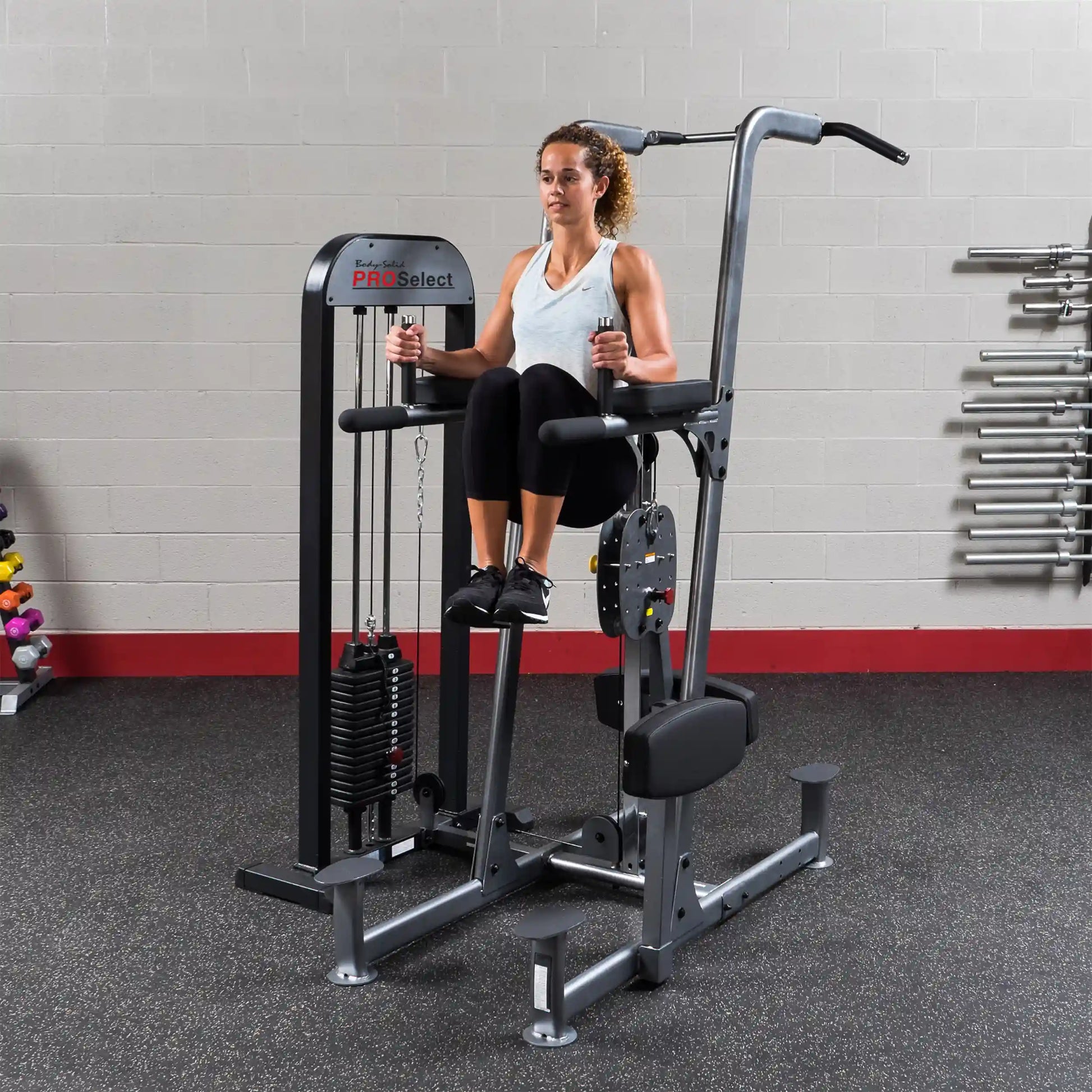 Woman using Body-Solid Pro Select knee raise machine in gym.