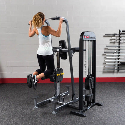 Woman using Body-Solid PRO Select pull-up machine with weight assist in gym.