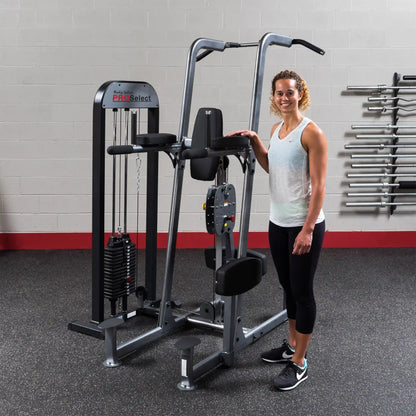 Woman standing beside Body-Solid ProSelect weight machine in gym.