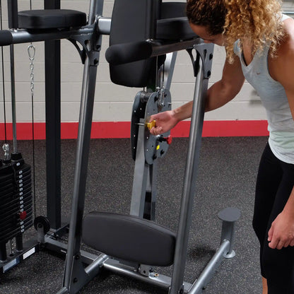 Woman adjusting a weight machine in a gym, demonstrating equipment use.