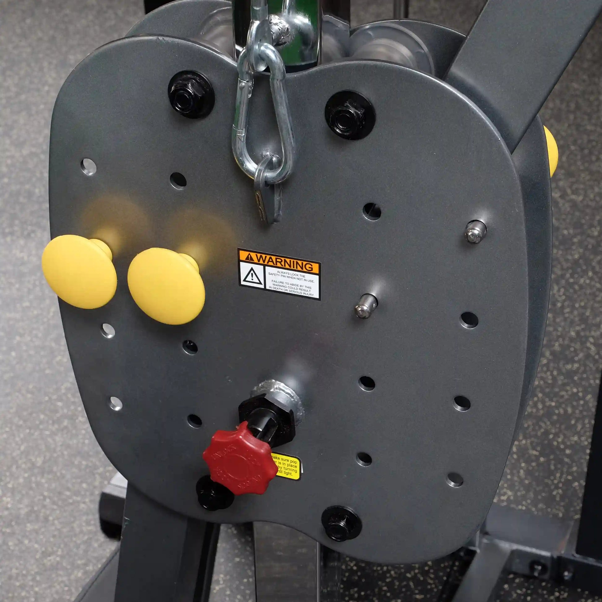 Weight machine adjustment panel with yellow grips and red knob for gym equipment setup.