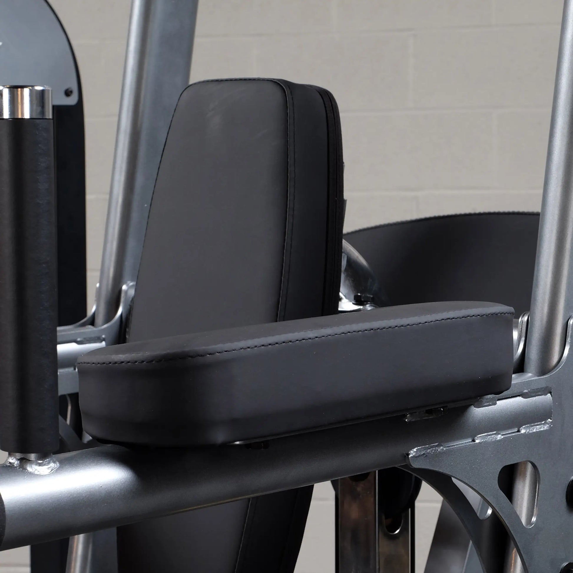 Black padded armrest on gym machine with steel frame.