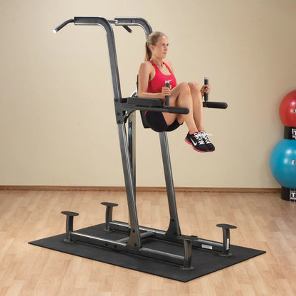 Woman using power tower for knee raises in a home gym.