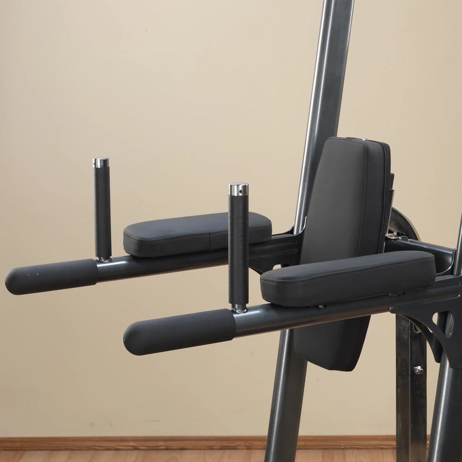 Power tower dip station with padded armrests and back support in black.