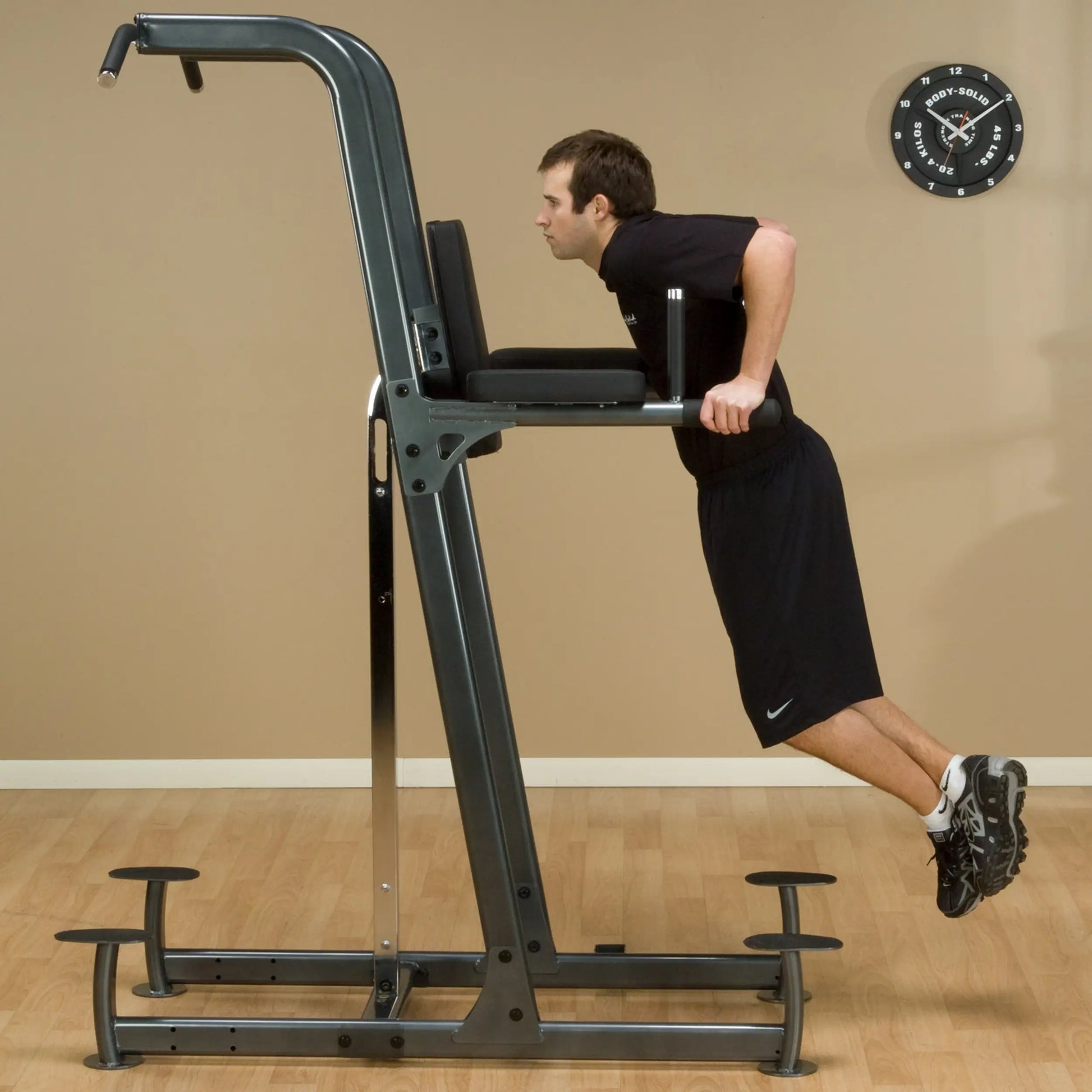 Man performing tricep dips on Body-Solid power tower in home gym setting.