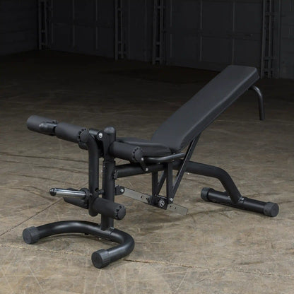 Adjustable black weight bench with leg extension in a gym setting.
