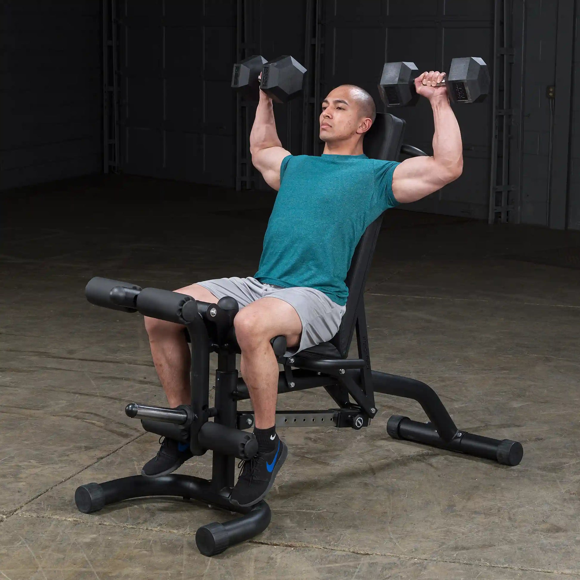 Man lifting dumbbells on adjustable weight bench in gym.