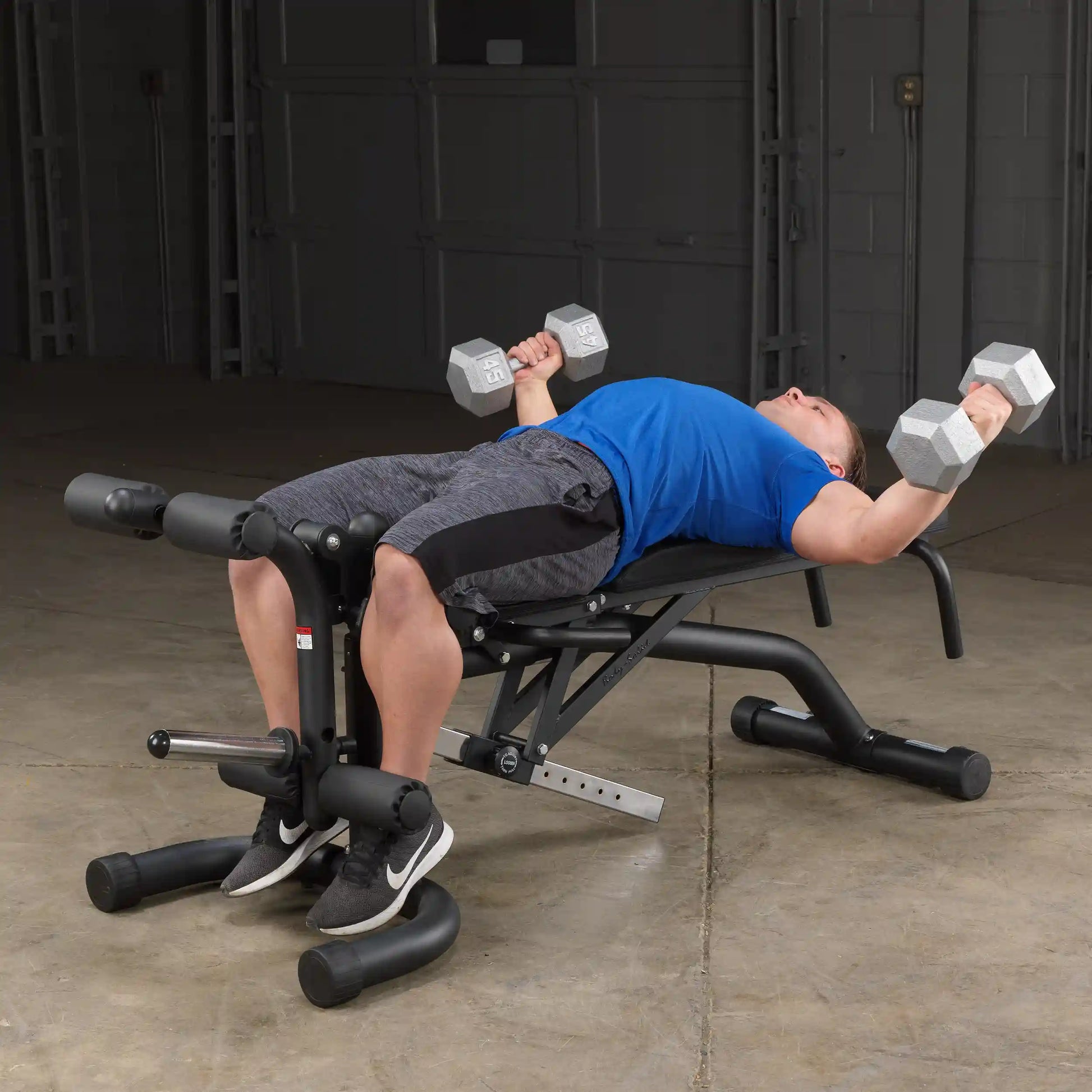 Man performing dumbbell chest fly on adjustable weight bench.