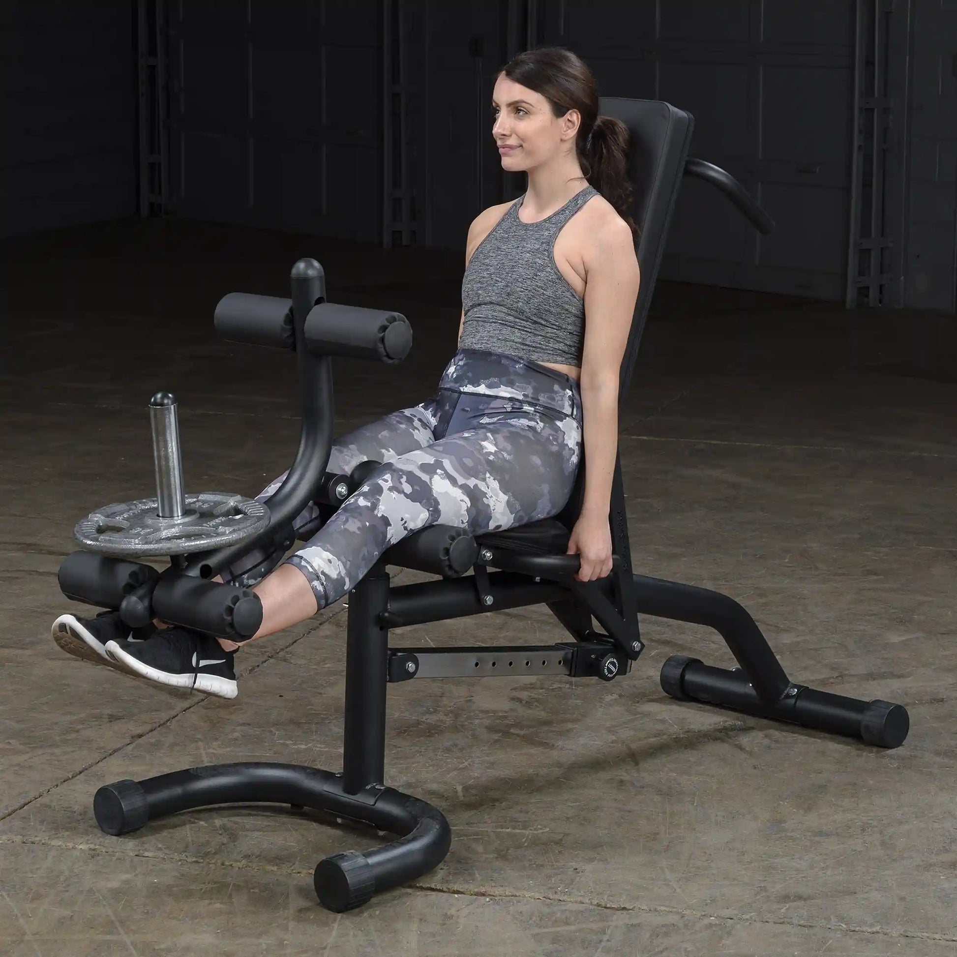 Woman using leg extension machine for a workout in a gym.