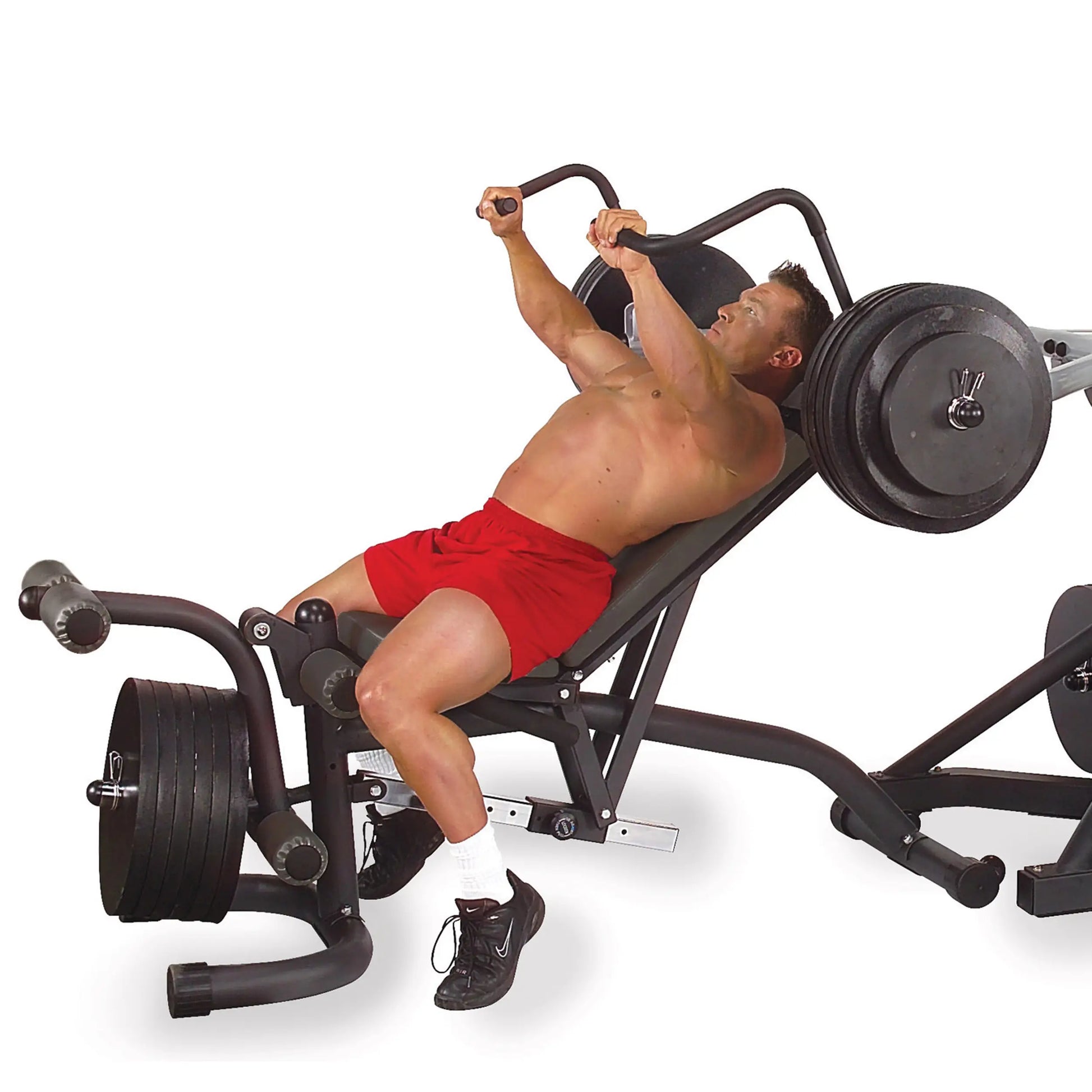 Man using a seated leg press machine, wearing red shorts, for strength training.
