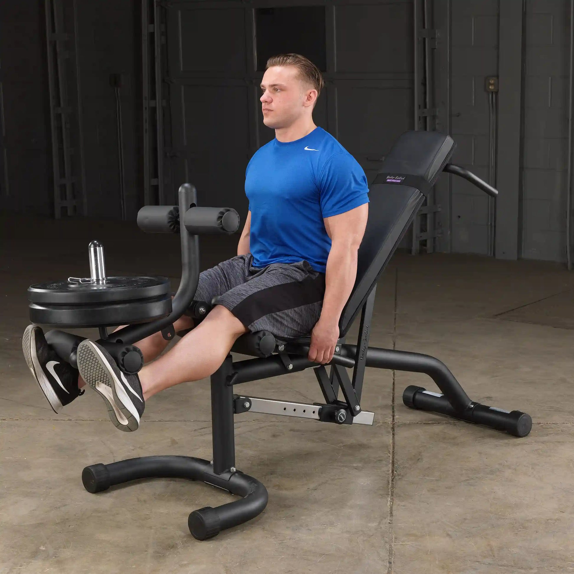 Man using Body Champ leg extension machine in blue shirt.