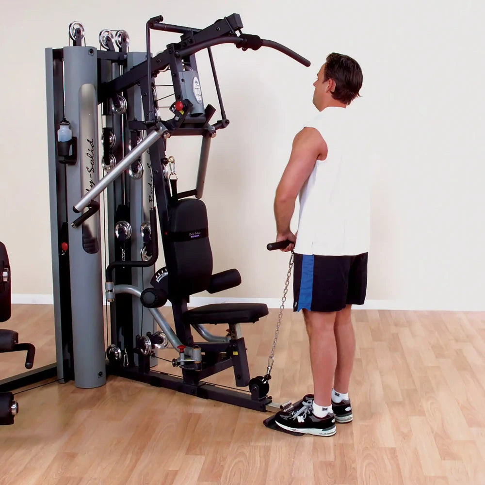 Man using Body-Solid home gym for tricep exercises on hardwood floor.