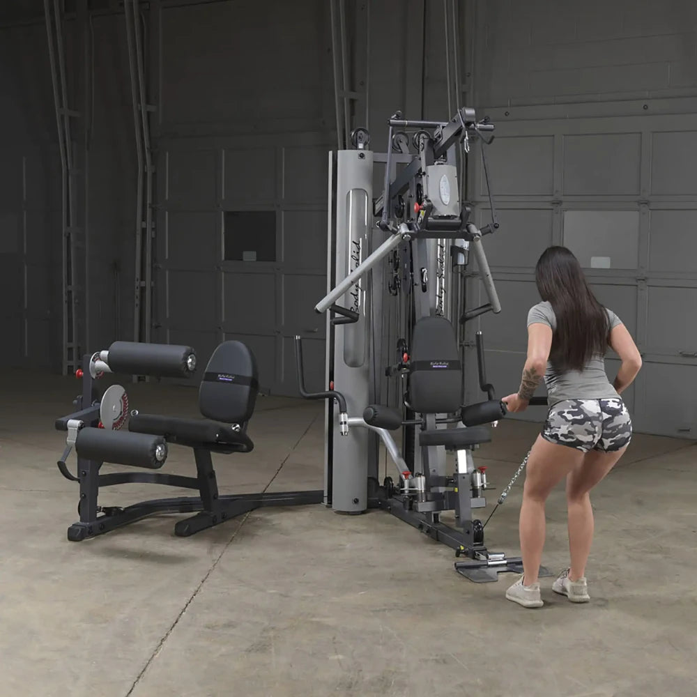 Woman using Body-Solid home gym equipment in a garage setting.