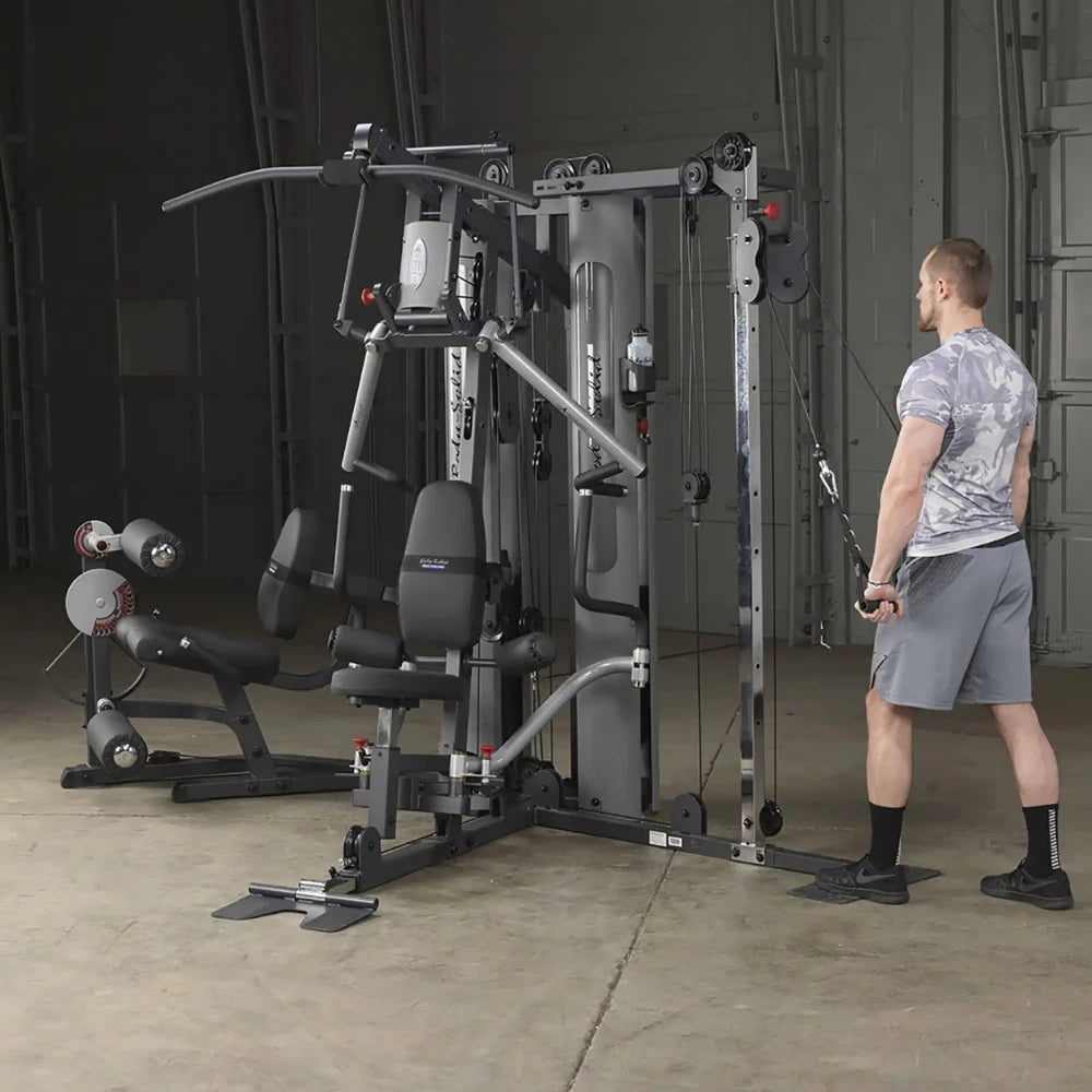 Man using Body-Solid home gym with cable machine in a concrete-floored room.