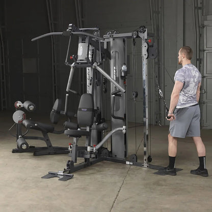 Man using Body-Solid home gym with cable machine in a concrete-floored room.
