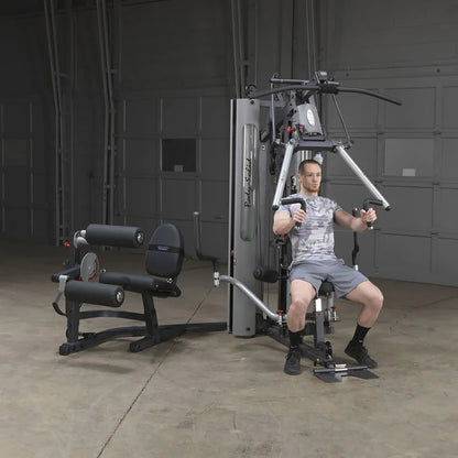 Man using Body-Solid home gym machine in a garage setting for strength training.