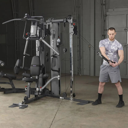 Man using Body-Solid home gym with cable crossover in a gray workout outfit.