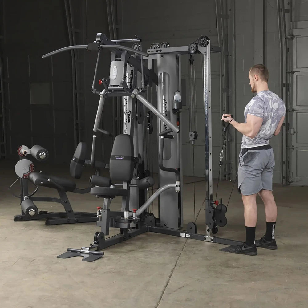 Man using Body-Solid home gym with cable machine in a gray workout room.