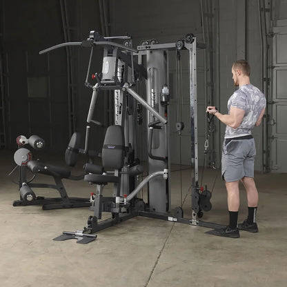 Man using Body-Solid home gym with cable machine in a gray workout room.
