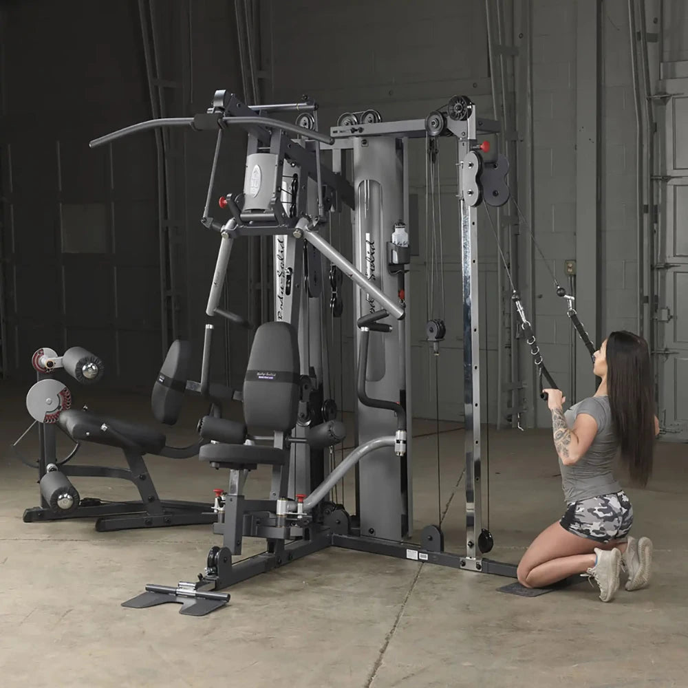 Woman using Body-Solid home gym with cable pulleys for strength training.
