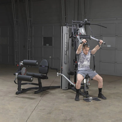 Man using Body-Solid gym machine with adjustable pulleys in a garage gym.