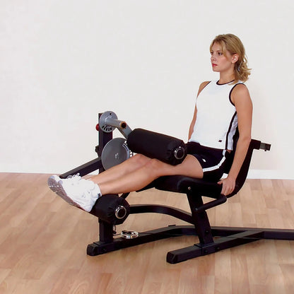 Woman using a black leg extension machine in a gym for strength training.
