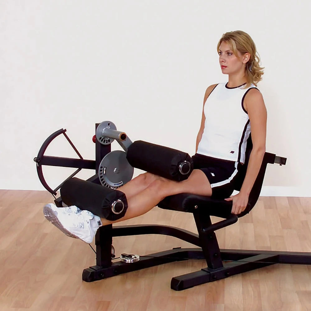 Woman using Body-Solid leg extension machine in a gym setting.