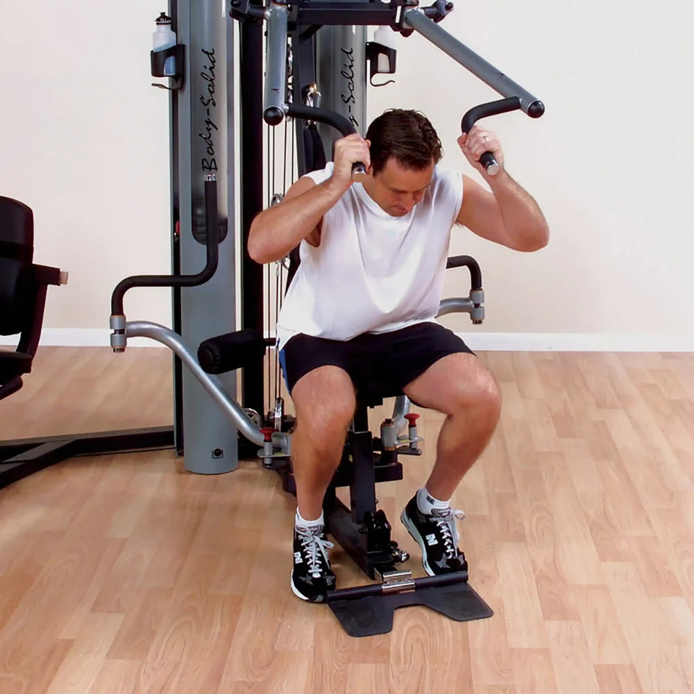 Man exercising on Body-Solid home gym with seated row, wearing black shorts and sneakers.