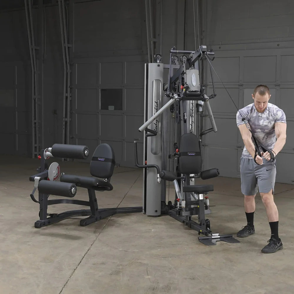 Man using Body-Solid home gym with cable machine in a garage setting.