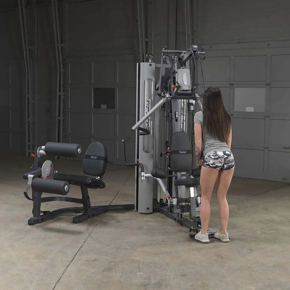 Woman using Body-Solid G9S compact home gym with dual weight stacks in a garage setting.