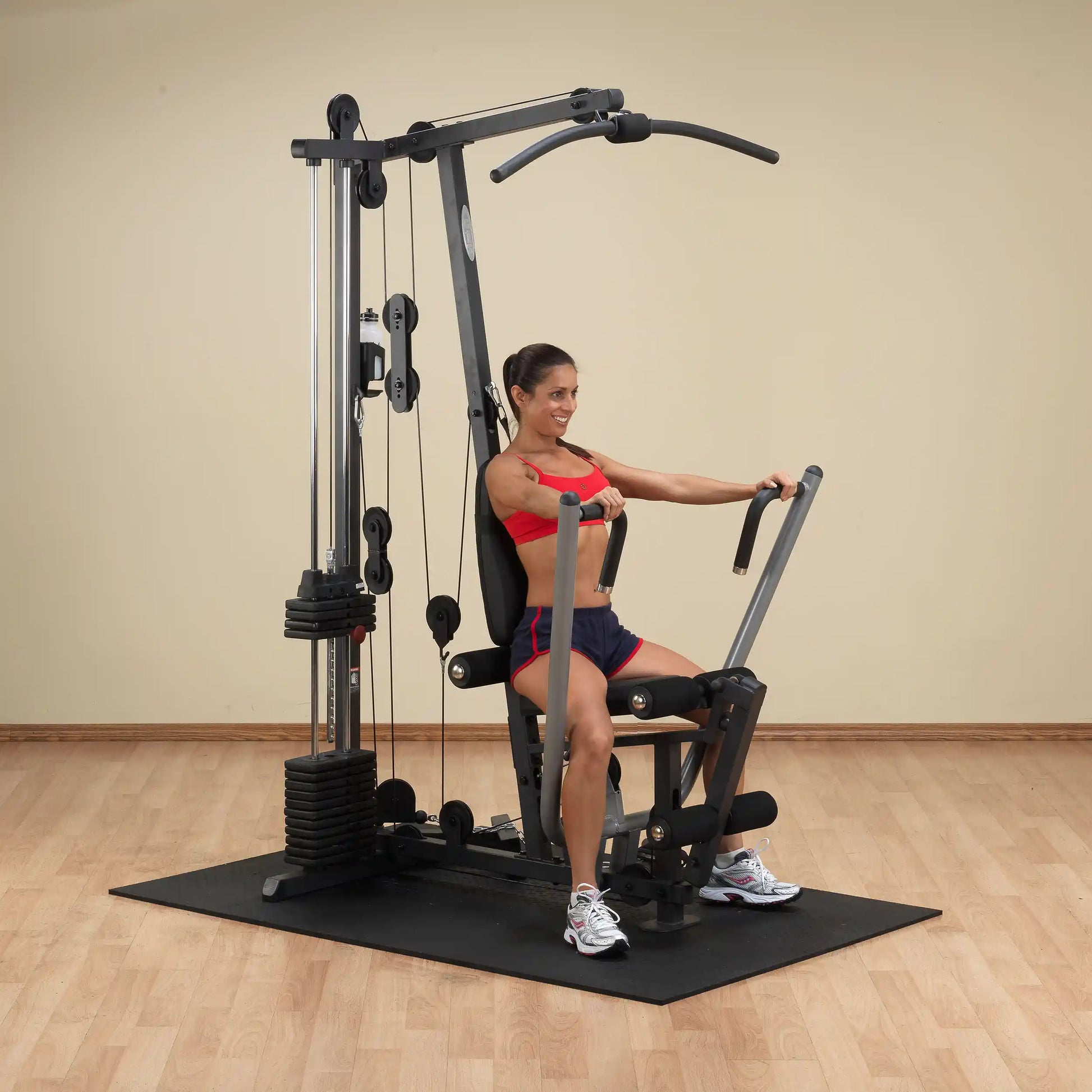 Woman using a home gym machine in red sportswear for strength training.