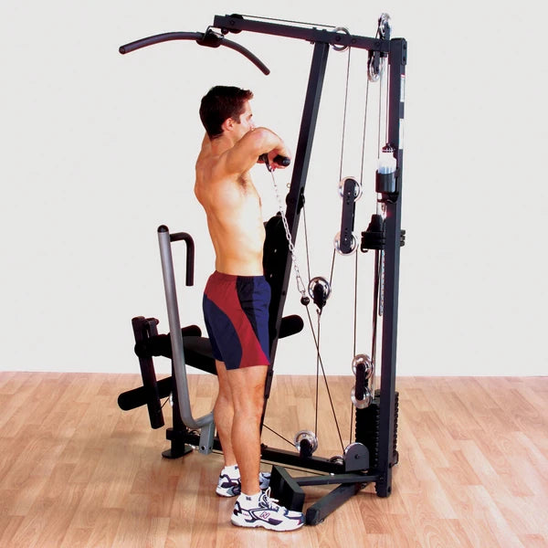 Man using multi-gym machine with cable pulley for strength training.