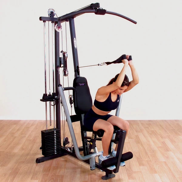 Woman using a Bowflex home gym for strength training on a hardwood floor.
