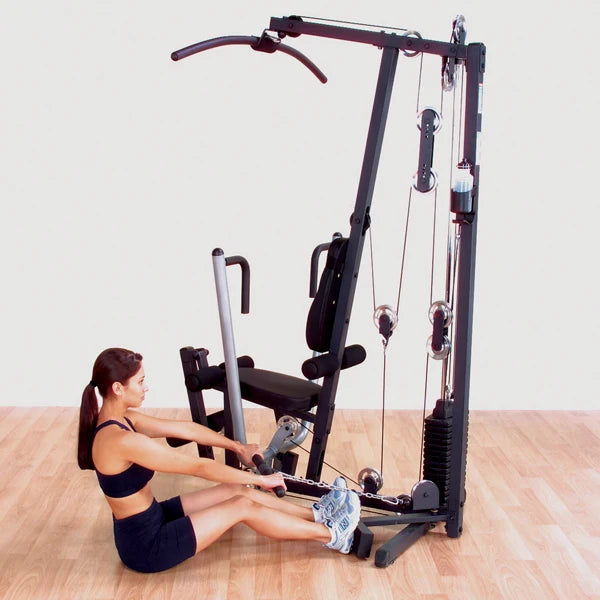 Woman using a home gym machine with pulleys for strength training.