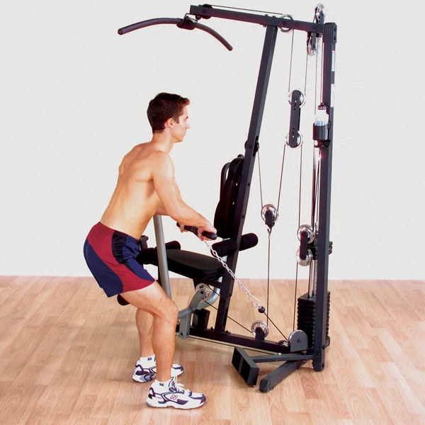 Man using a home gym cable machine for strength training on hardwood floor.