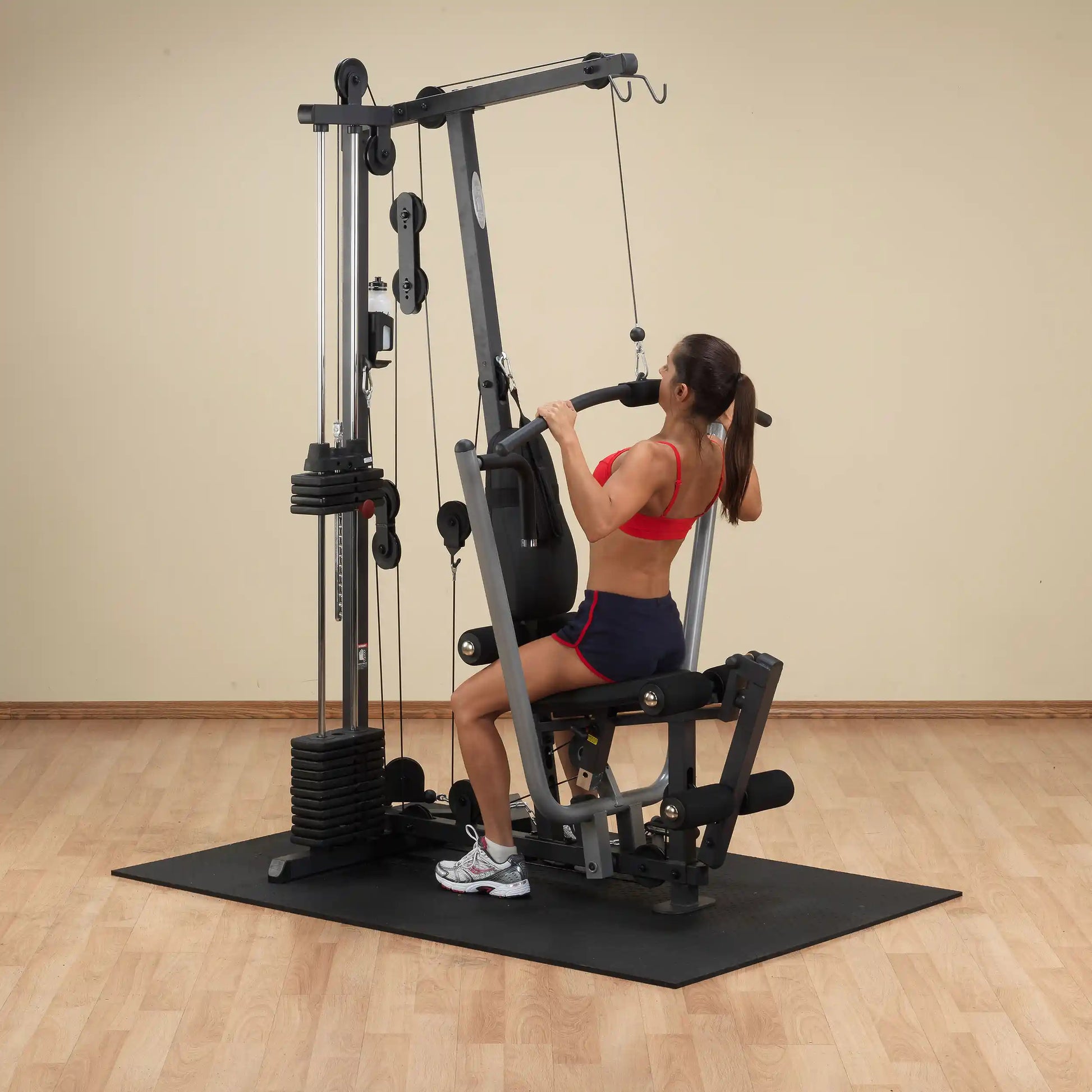 Woman using a multi-station gym machine for strength training.