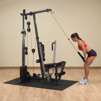 Woman using a cable machine for tricep exercises in a gym.